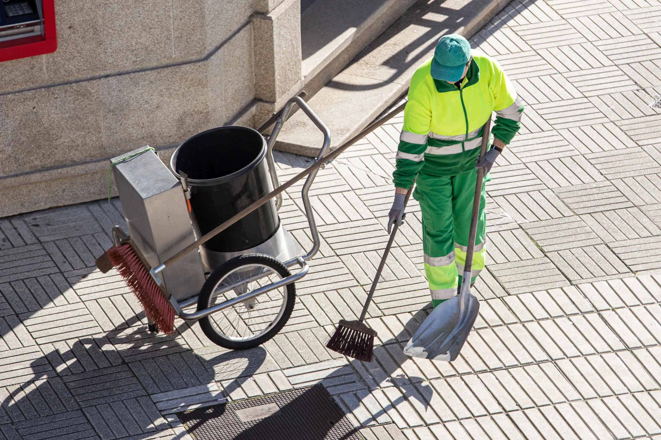 Baureinigung in Kiel: Reinigungskraft kehrt den Gehweg vor einer Baustelle