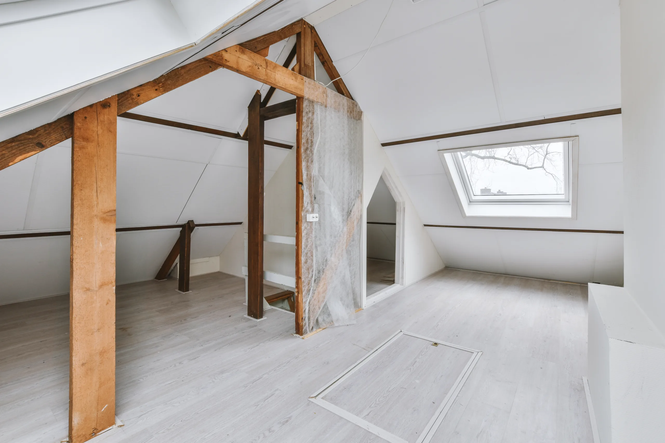 Dachgeschossausbau in Kiel: freigelegte alte Holzbalken, neuer heller Boden und wei&szlig;e W&auml;nde