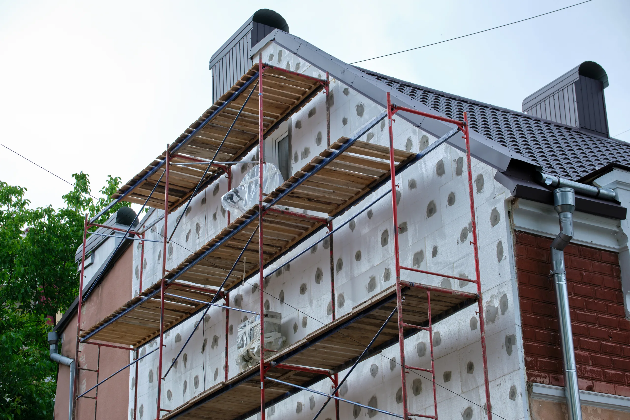 Fassadensanierung in Kiel: Ger&uuml;st am Wohnhaus, D&auml;mmplatten werden an der Fassade gesetzt